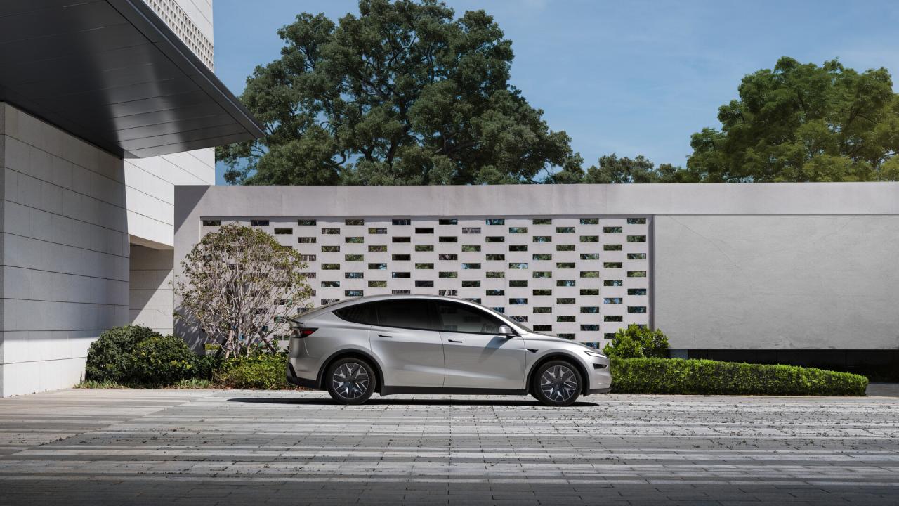 Tesla Model Y L v bočním profilu před moderní budovou