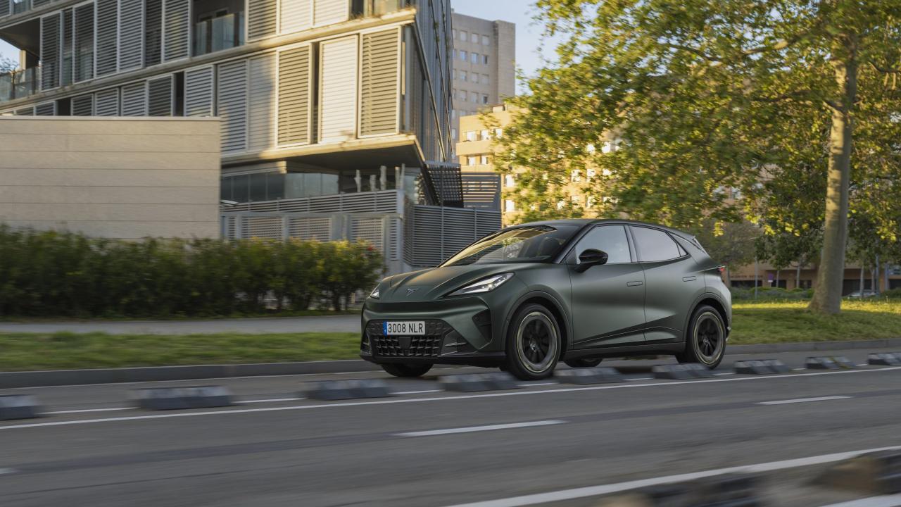 CUPRA Raval v tmavě zelenošedém provedení při jízdě městskou ulicí, levý přední boční pohled | zdroj: seat-cupra-mediacenter.com