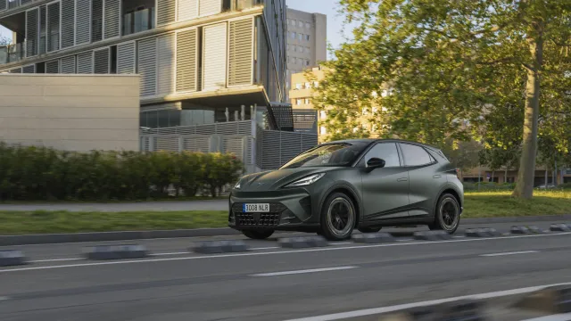 CUPRA Raval v tmavě zelenošedém provedení při jízdě městskou ulicí, levý přední boční pohled | zdroj: seat-cupra-mediacenter.com